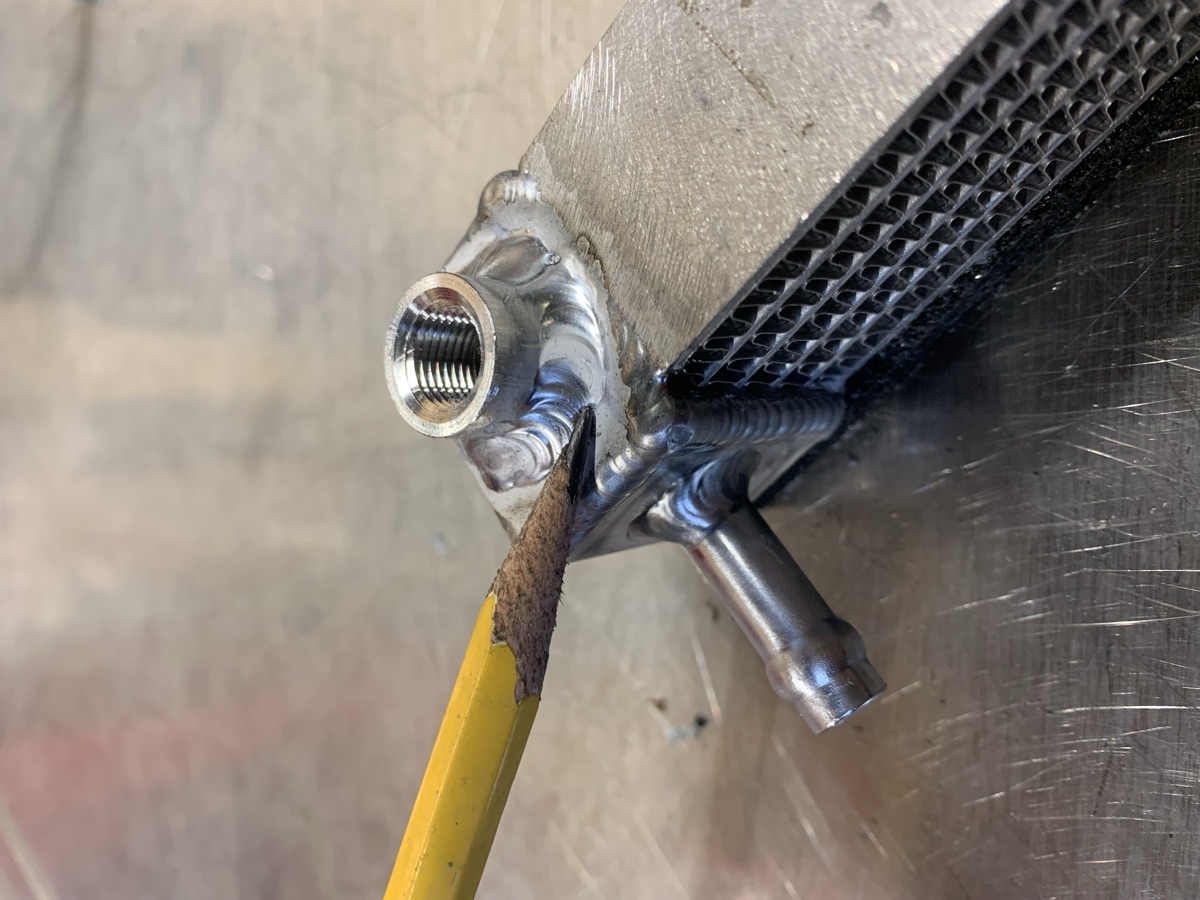 Threaded aluminum port welded onto a radiator core, pencil for scale