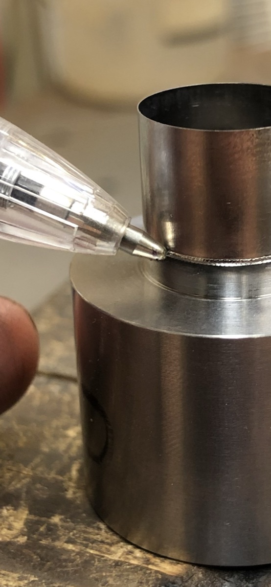 Thin Hastelloy cylinder micro laser welded to a stainless machined base, pen tip for scale