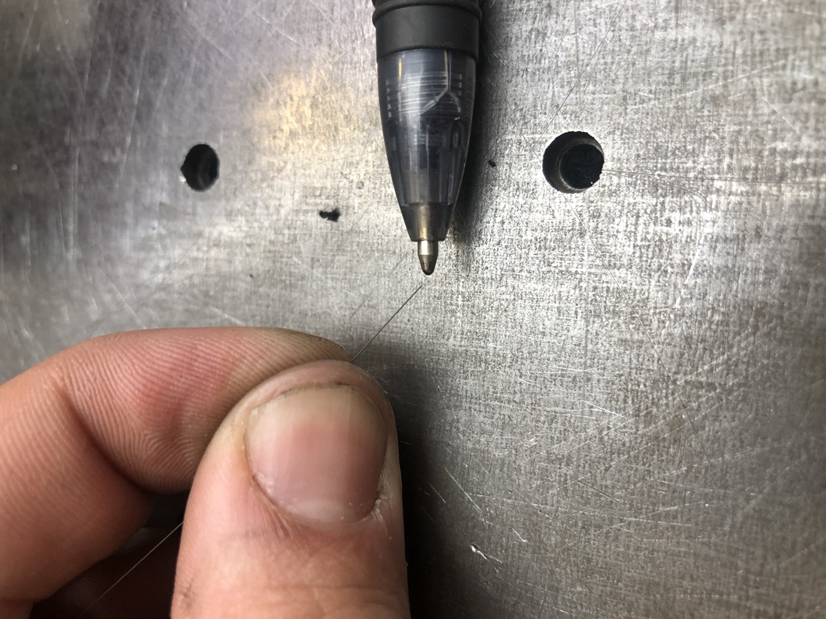 Hair-thin micro laser welding wire beside a ballpoint pen tip for scale
